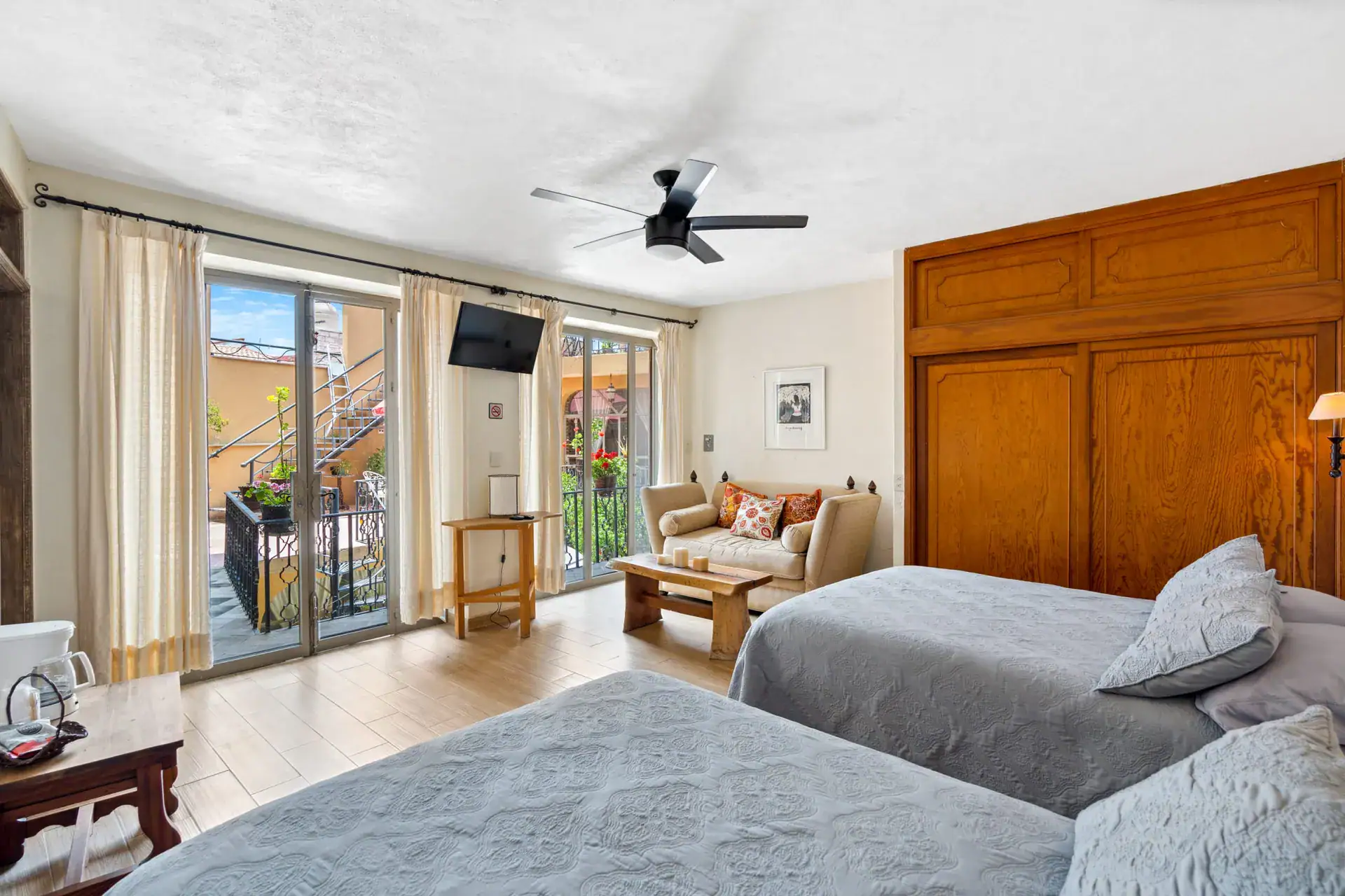 Casa Los Helechos, bedroom with a gray bedspread, sofa and sliding doors to a balcony, San Miguel de Allende