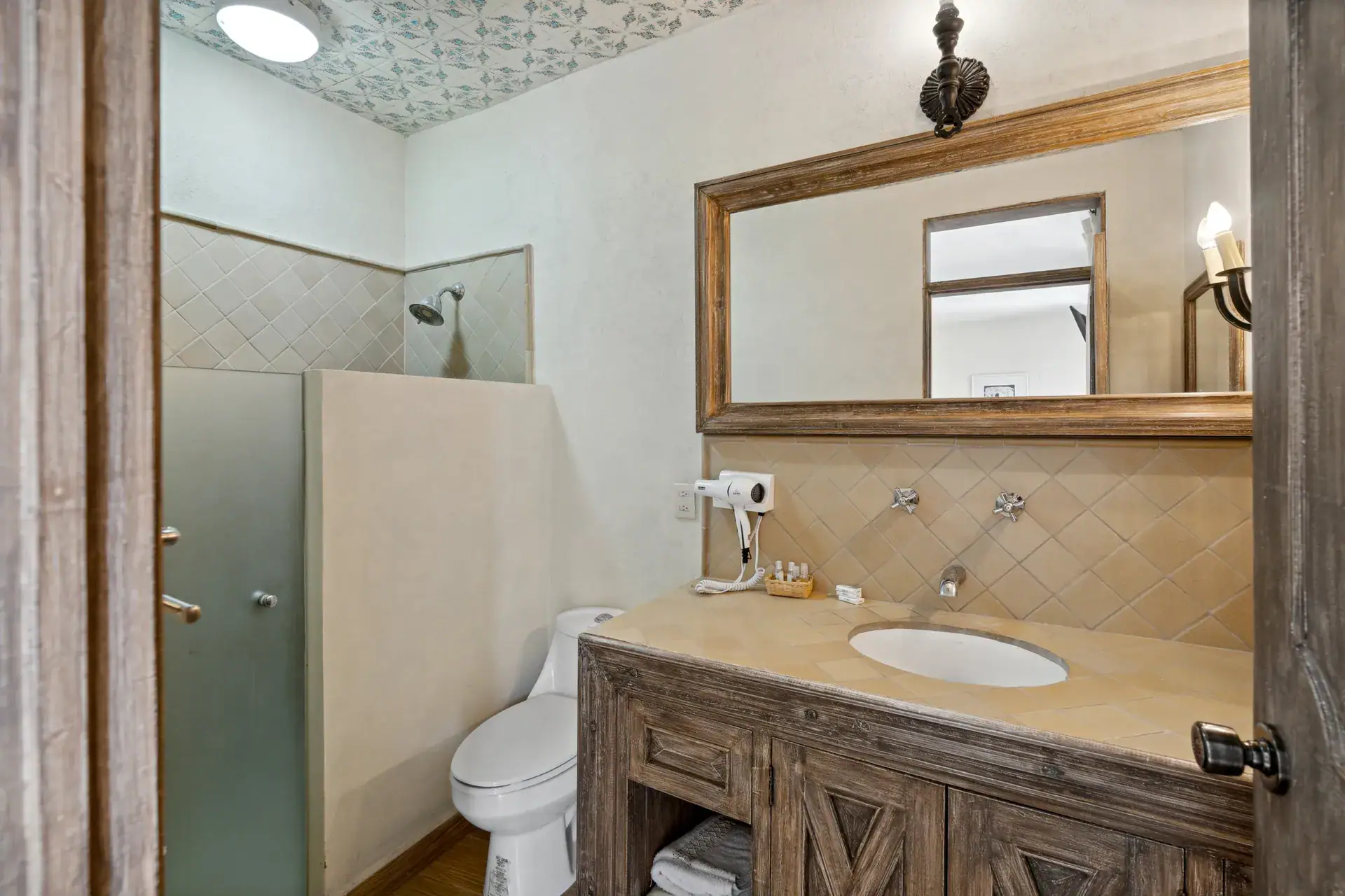 Casa Los Helechos, bathroom with a stone-top vanity, a mirror and a frosted glass shower, San Miguel de Allende