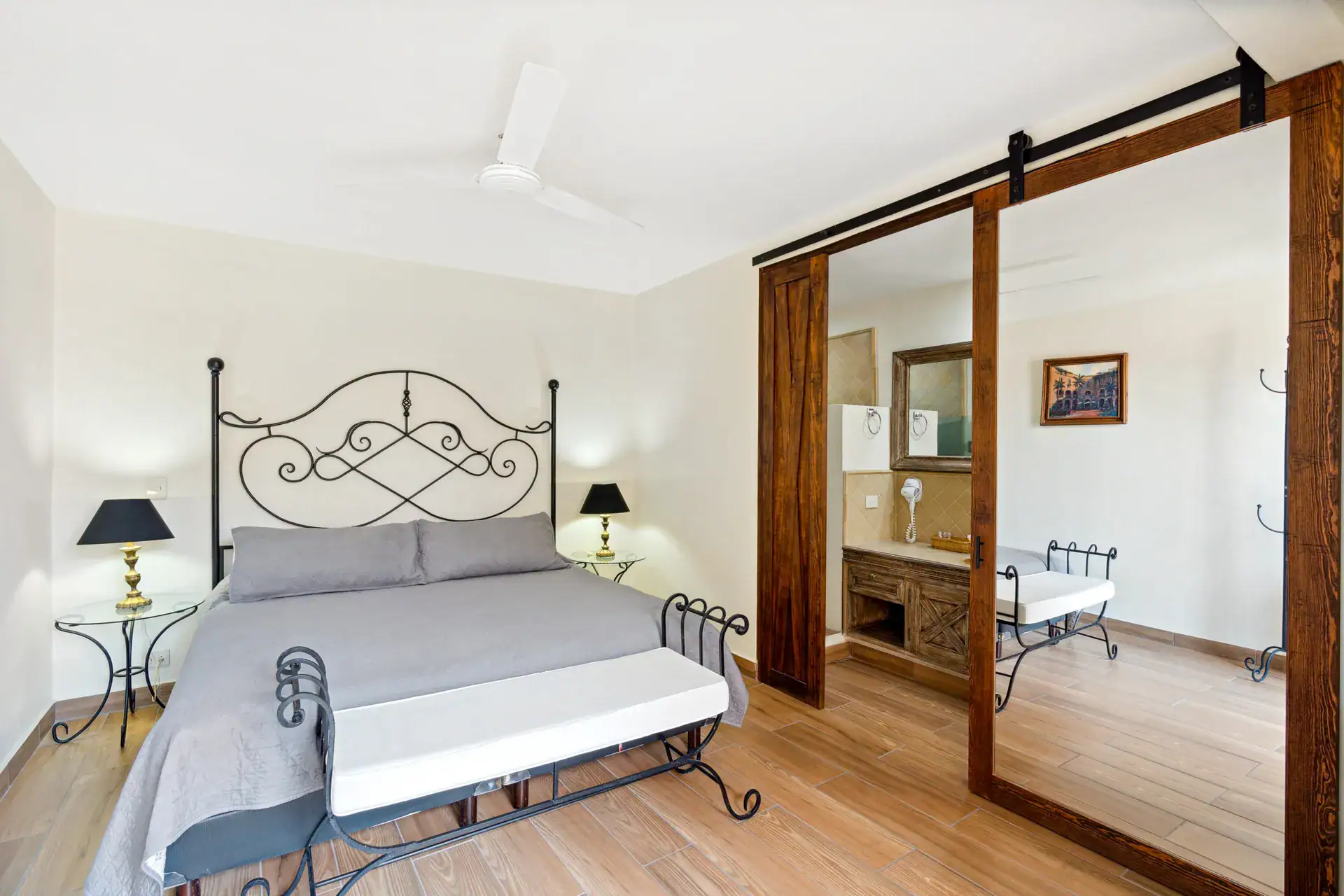 Casa Los Helechos, bedroom with an iron headboard and a barn-door closet and bathroom, San Miguel de Allende