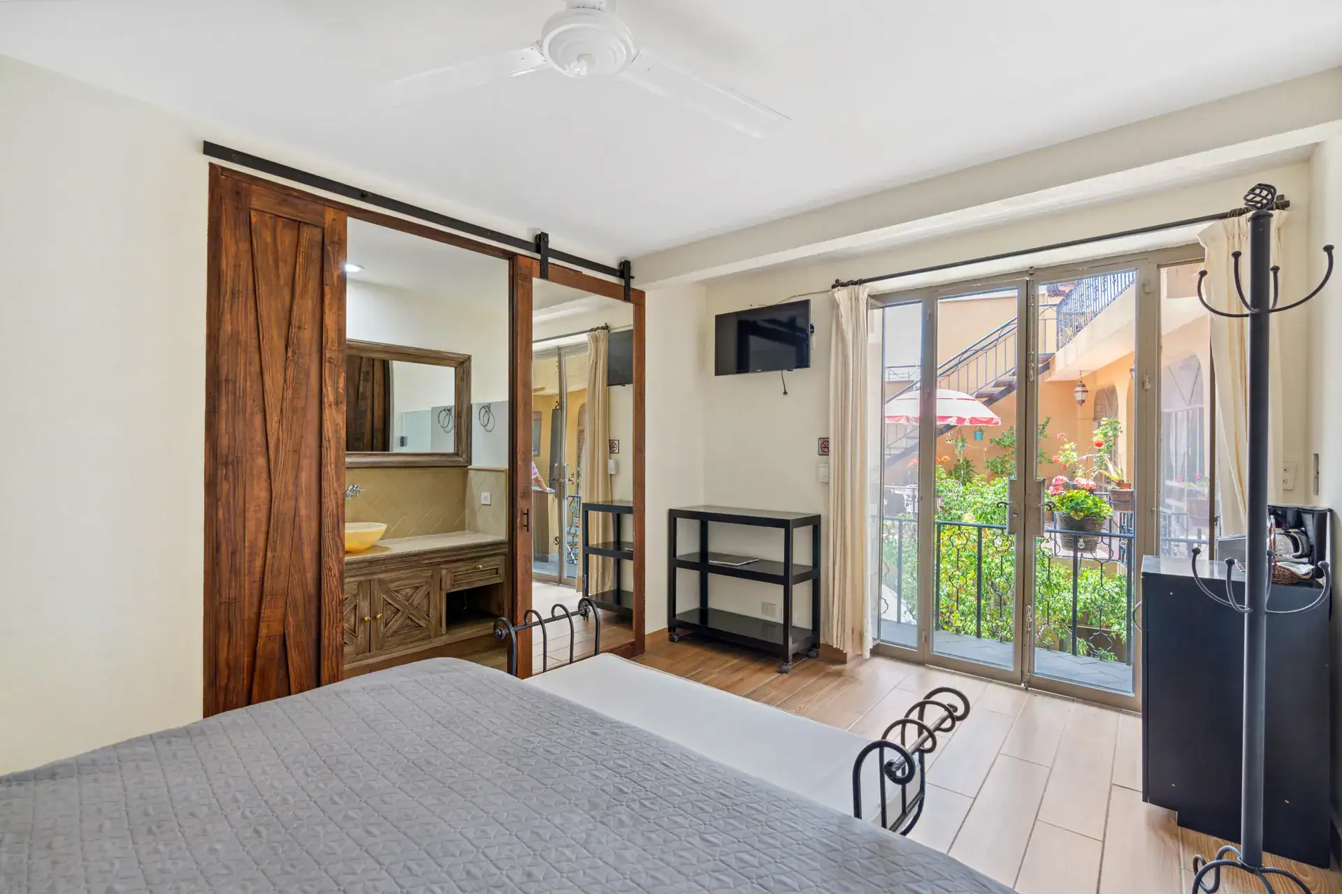 Casa Los Helechos, bedroom with sliding glass doors to the courtyard and a barn-door bathroom, San Miguel de Allende