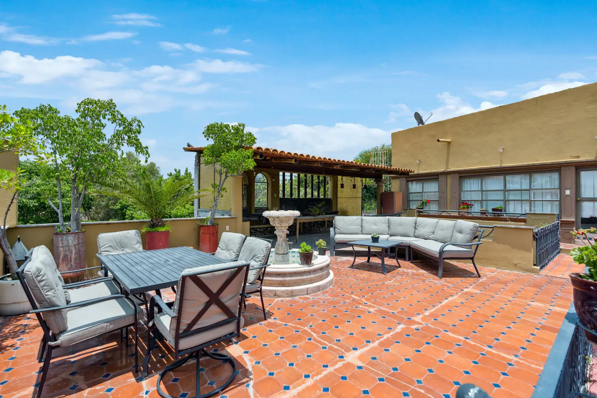 Casa Los Helechos, rooftop terrace with a patio dining set, a round fountain and a curved sofa, San Miguel de Allende