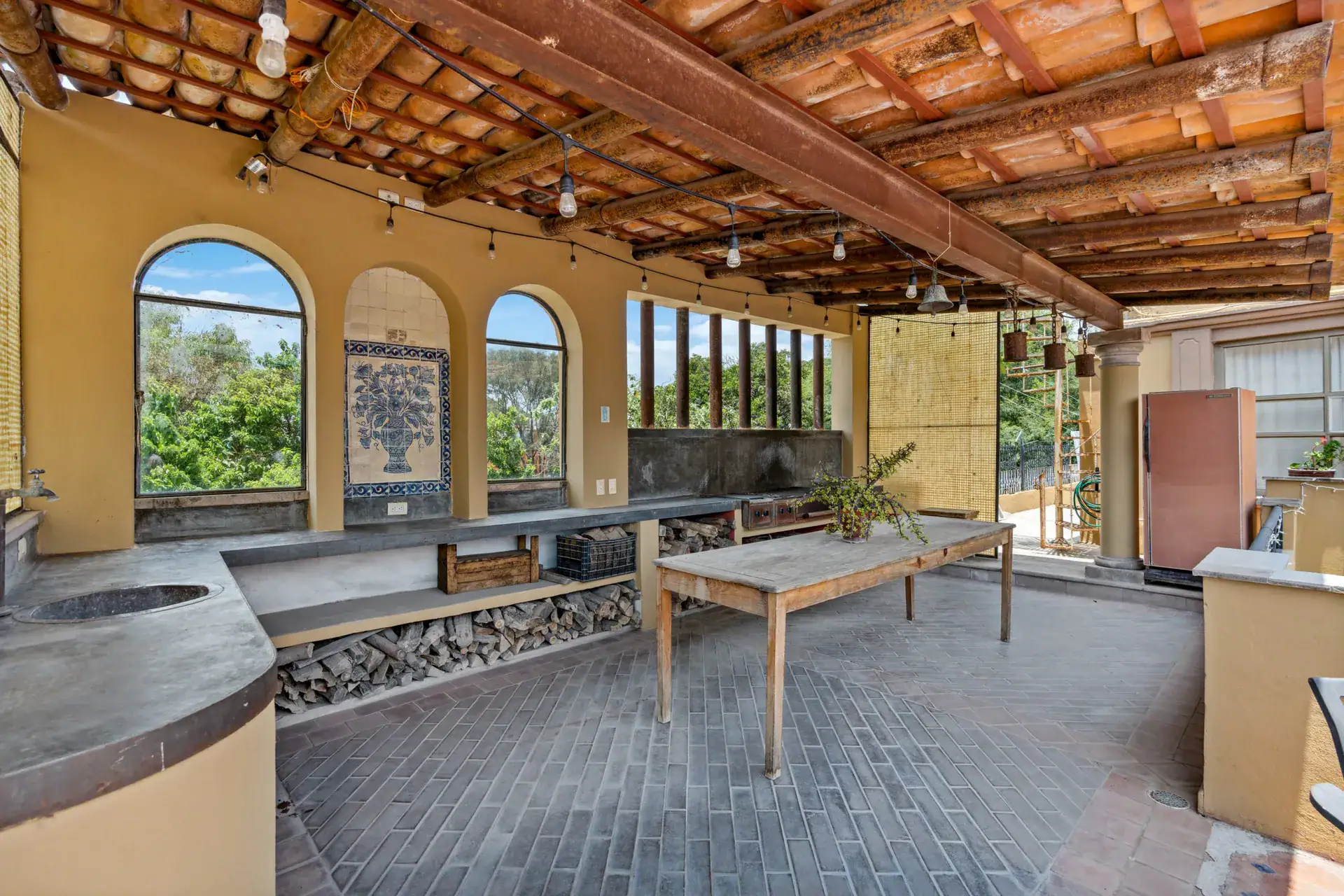 Casa Los Helechos, covered rooftop pavilion with a long table, a wood-fired grill and arched windows, San Miguel de Allende