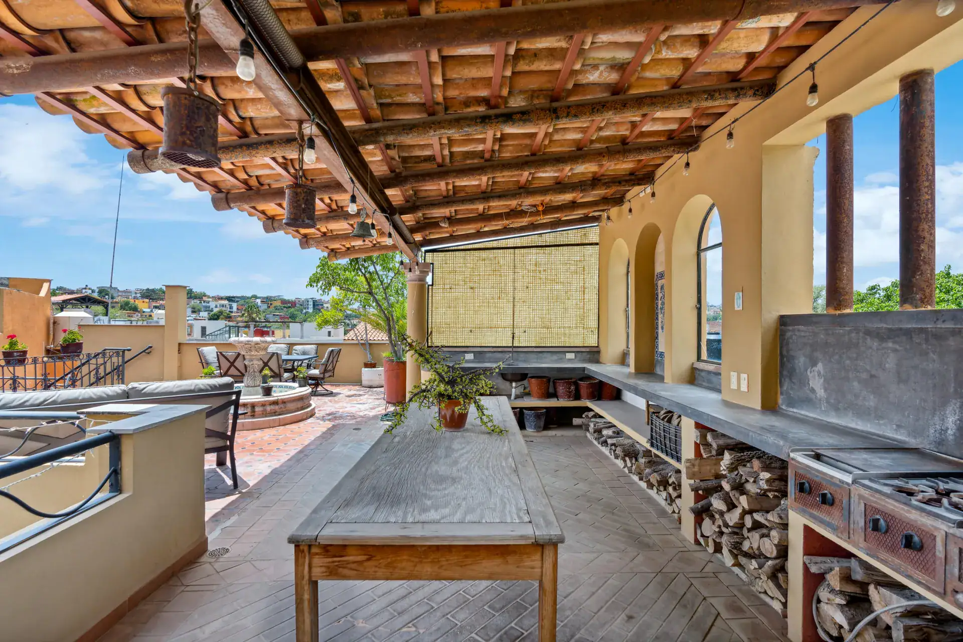 Casa Los Helechos, covered pavilion with a wood table, stacked firewood and a grill counter, San Miguel de Allende