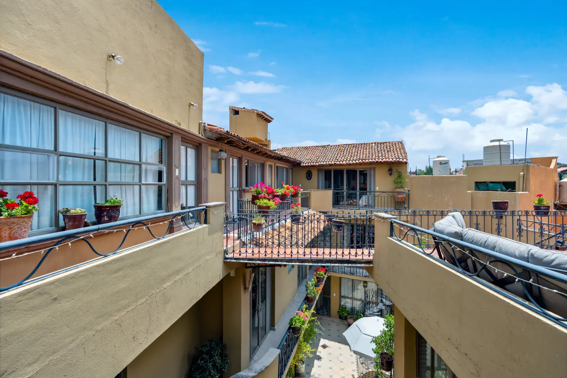 Casa Los Helechos, rooftop walkway beside the glass-walled suite and a view into the courtyard, San Miguel de Allende