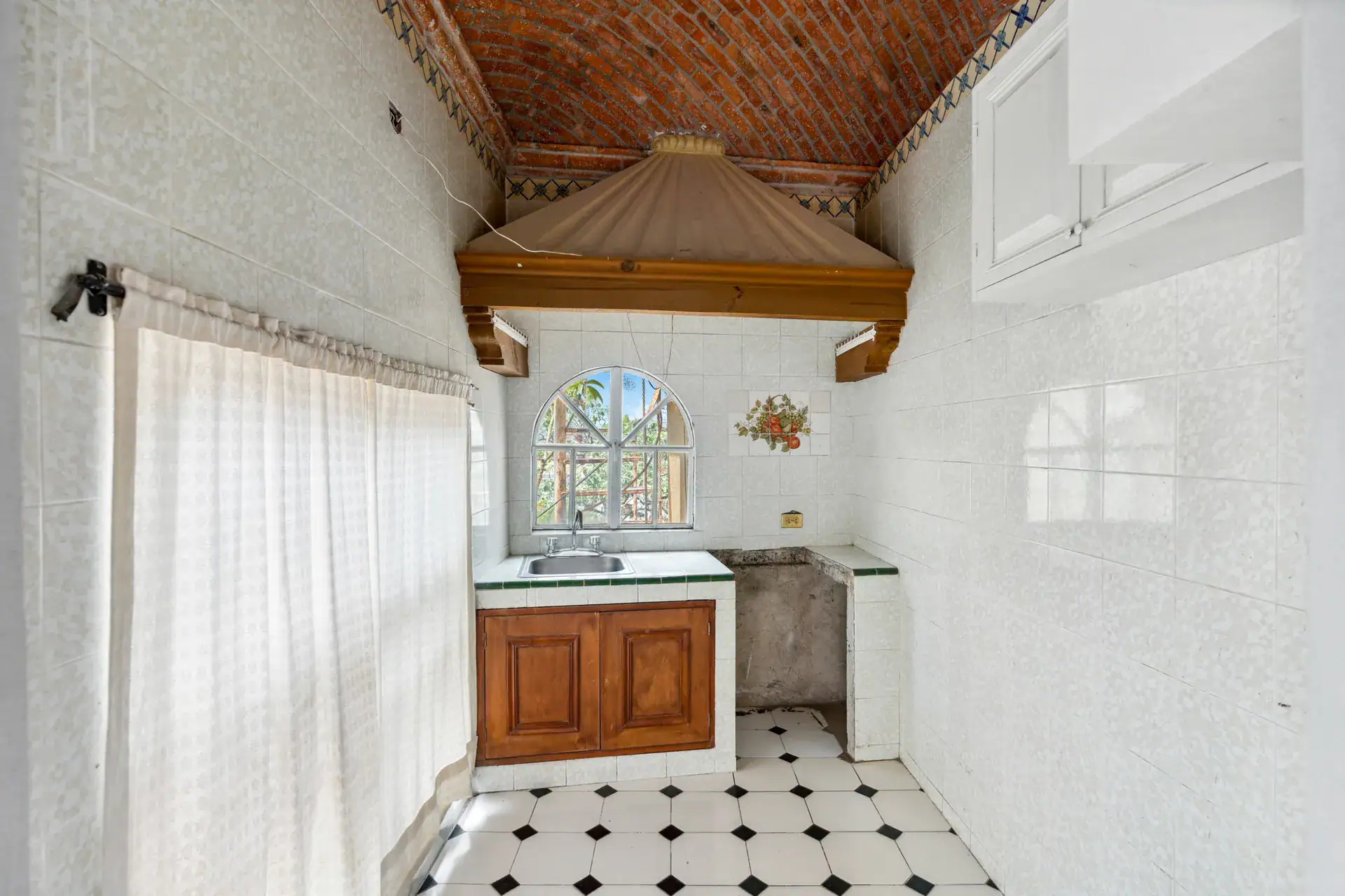 Casa Los Helechos, kitchenette with wood cabinets, an arched window and a brick vaulted ceiling, San Miguel de Allende