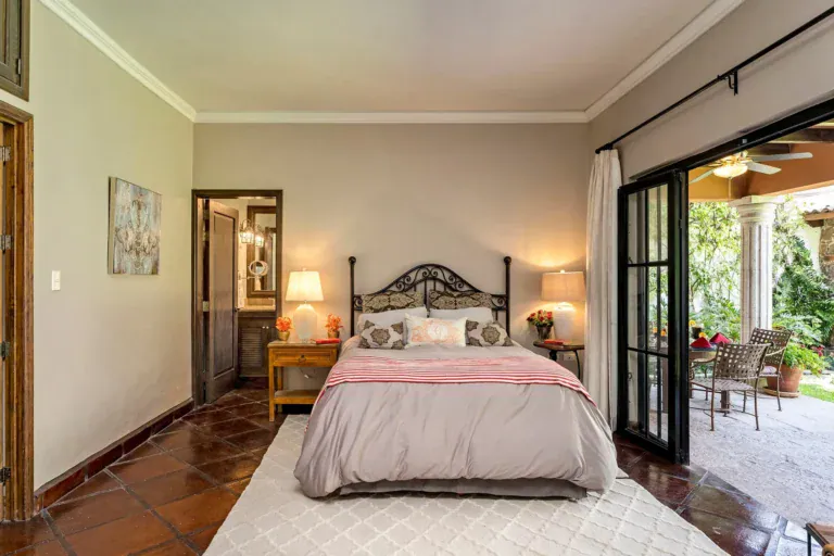 Casa Lua, primary bedroom with a wrought-iron bed and glass doors to the patio, San Miguel de Allende