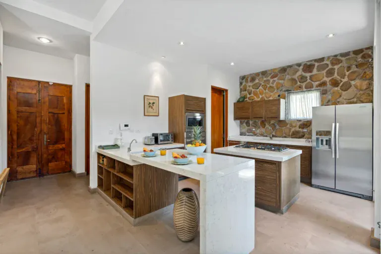 Casa Lula, kitchen with a stone-topped island, steel refrigerator and wood doors, San Miguel de Allende