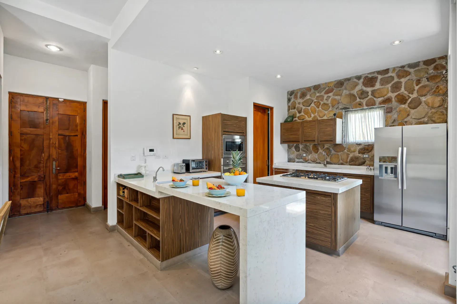Casa Lula, kitchen with a stone-topped island, steel refrigerator and wood doors, San Miguel de Allende