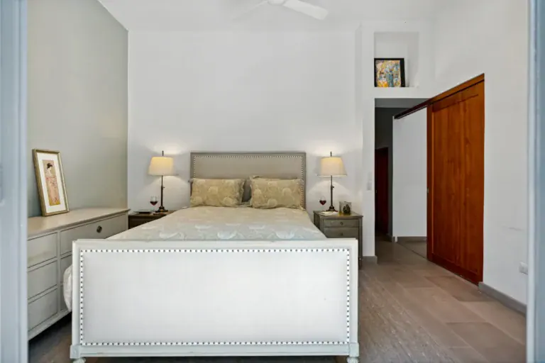 Casa Lula, bedroom with a white upholstered bed and wood doors, San Miguel de Allende