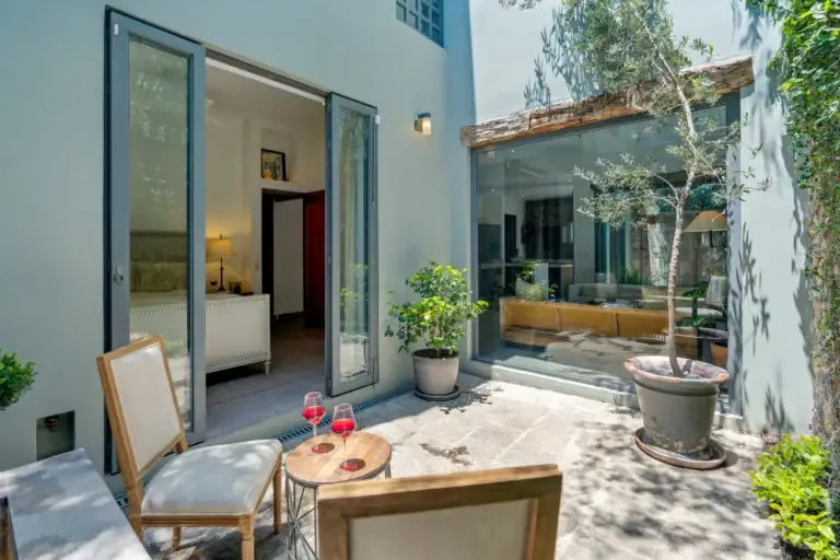 Casa Lula, courtyard with a glass wall, a lemon tree and a bistro table, San Miguel de Allende