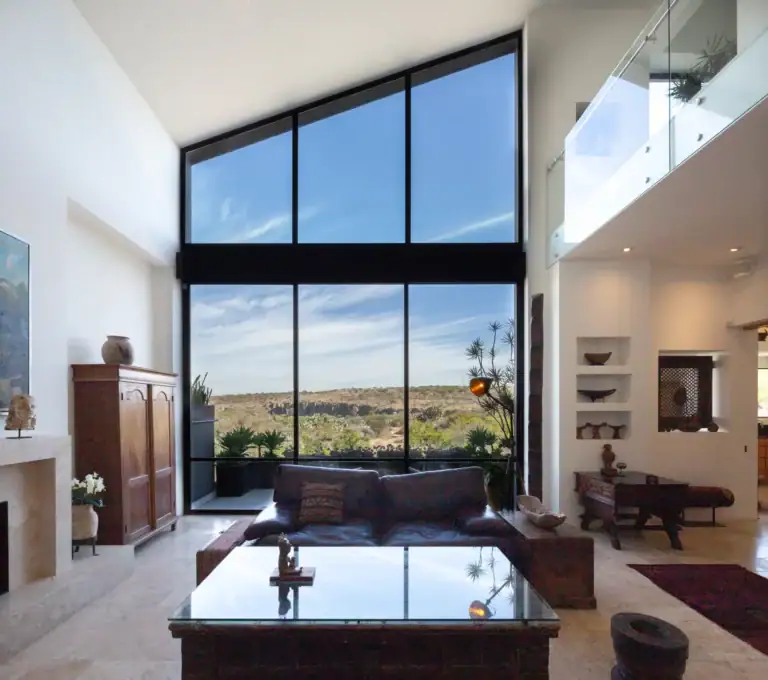 Casa Luz, double-height living room with floor-to-ceiling windows overlooking the valley and a glass-railed mezzanine, San Miguel de Allende