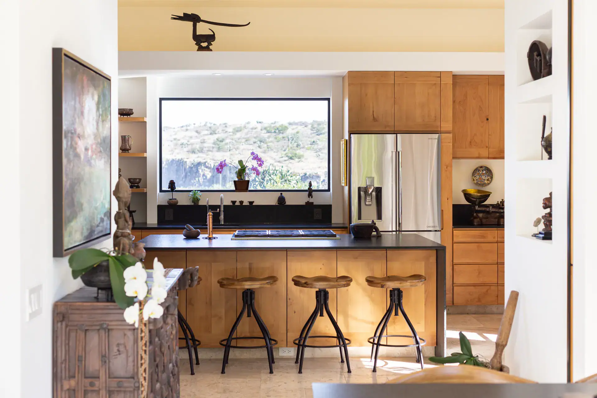 Casa Luz, kitchen with a wood island, black stools, stainless steel refrigerator and a window to the hills, San Miguel de Allende