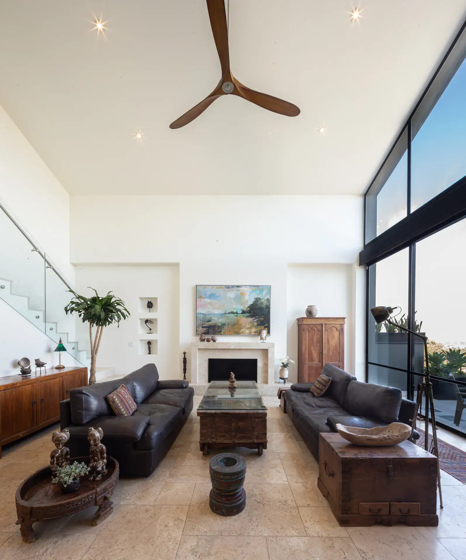 Casa Luz, living room with leather sofas, a fireplace and tall windows under a ceiling fan, San Miguel de Allende
