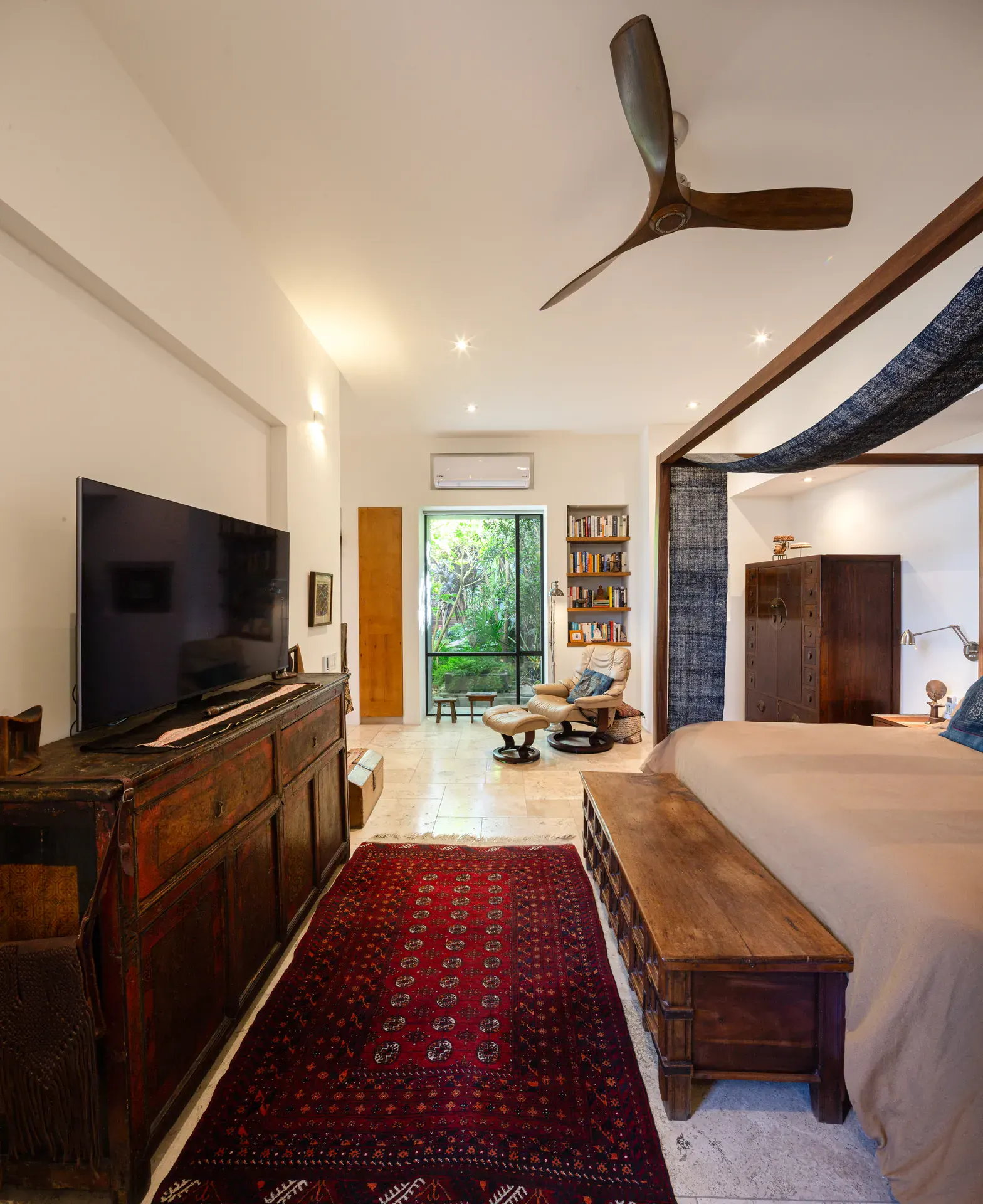 Casa Luz, bedroom with a canopy bed, television on a carved chest and a red runner rug, San Miguel de Allende