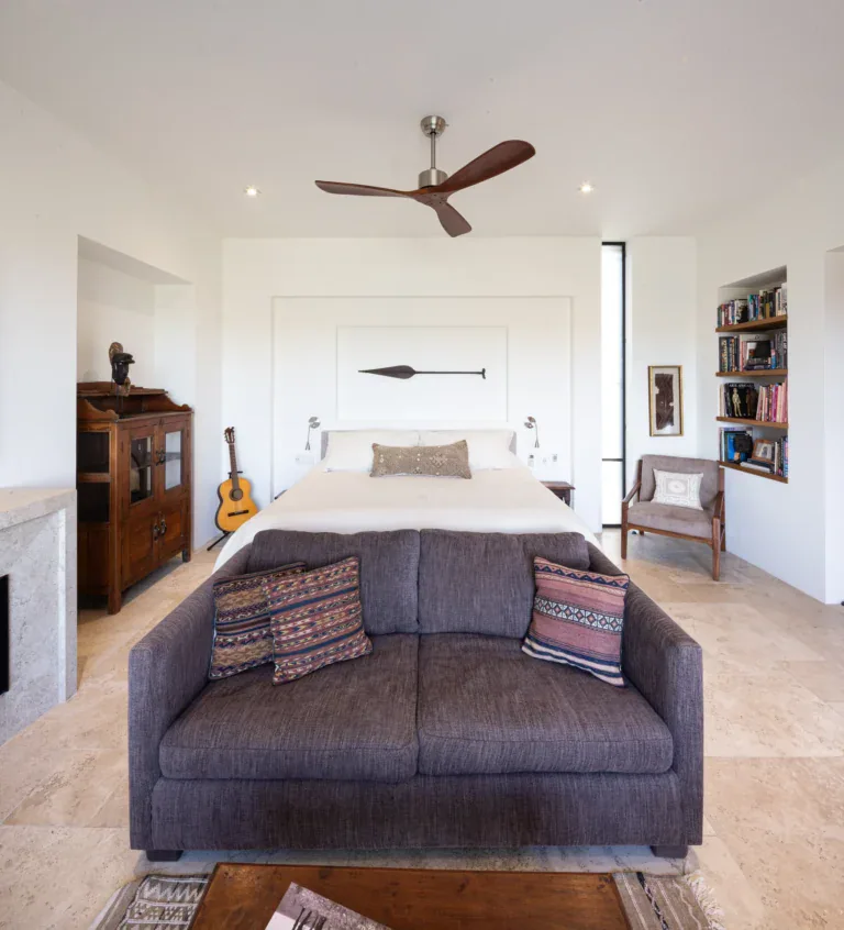 Casa Luz, bedroom with a gray sofa at the foot of the bed, built-in shelves and a ceiling fan, San Miguel de Allende