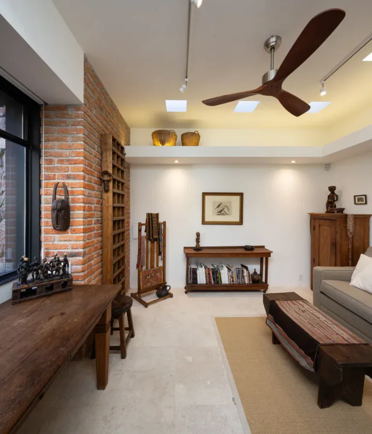 Casa Luz, study with a brick wall, wooden bench, bookshelves and an armchair, San Miguel de Allende