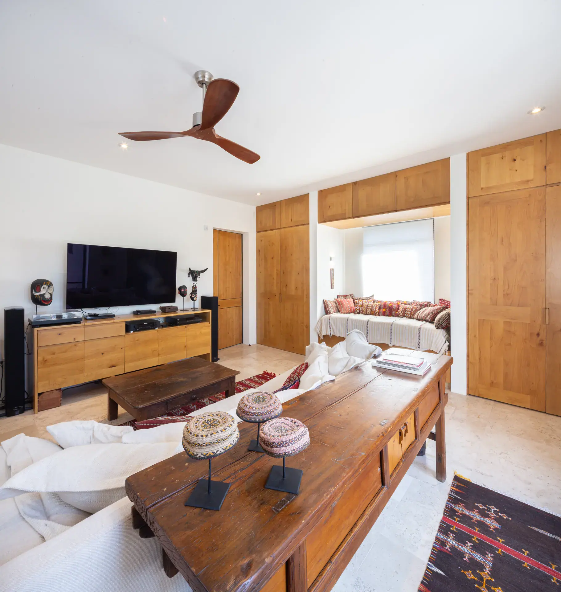 Casa Luz, media room with a wall-mounted television, wood console and white sofa, San Miguel de Allende