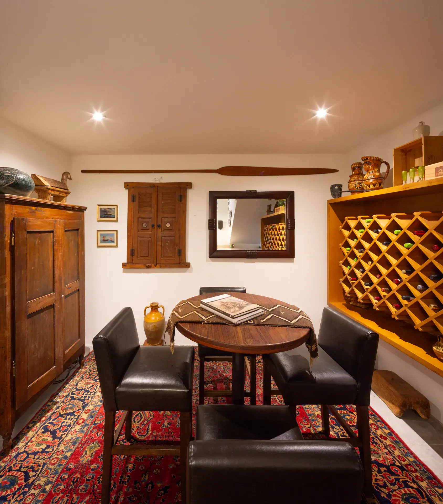 Casa Luz, wine room with a round table, leather chairs, wine rack and a red rug, San Miguel de Allende