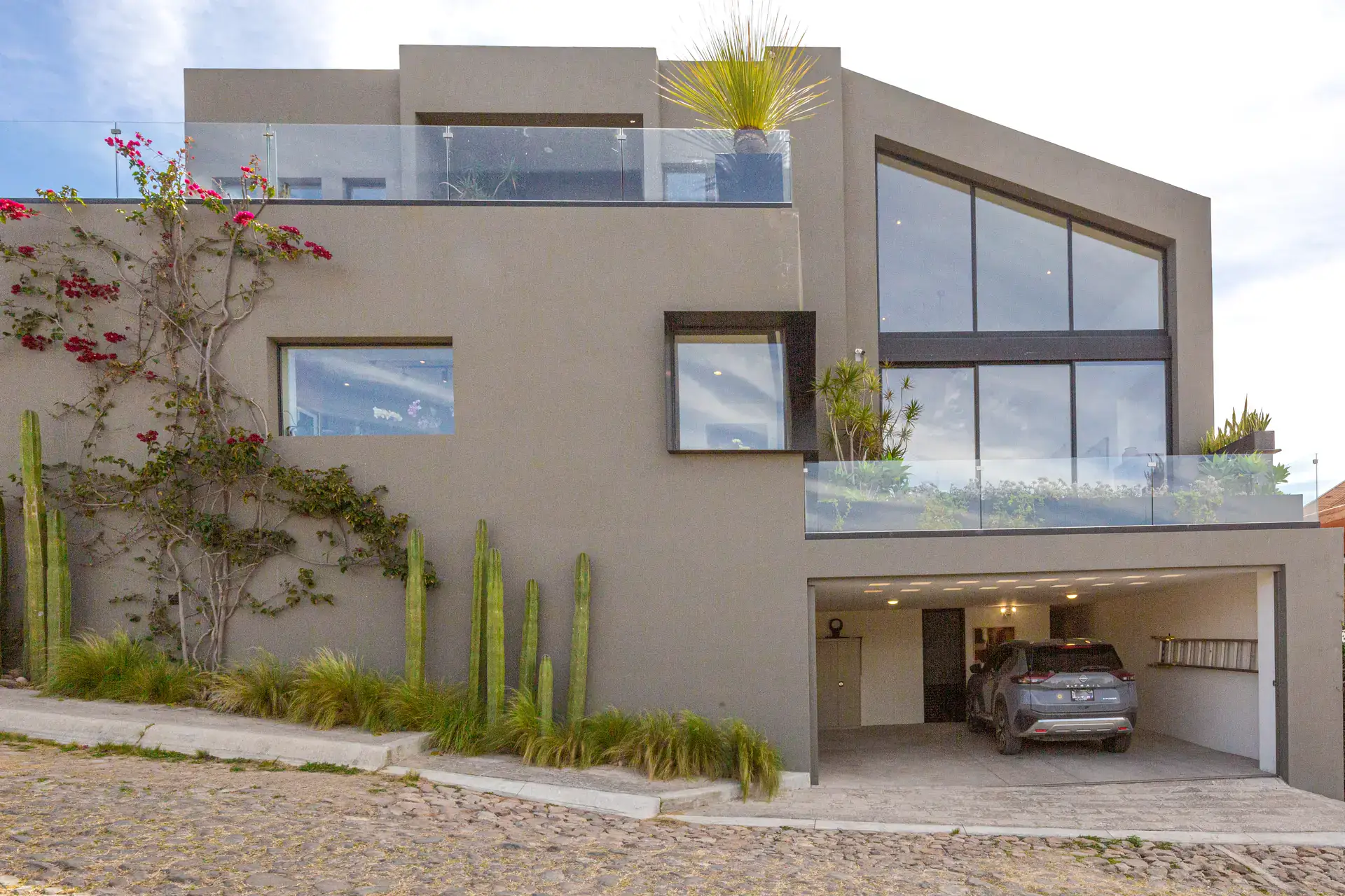 Casa Luz, exterior with a glass-railed terrace, large windows, bougainvillea and a covered garage, San Miguel de Allende