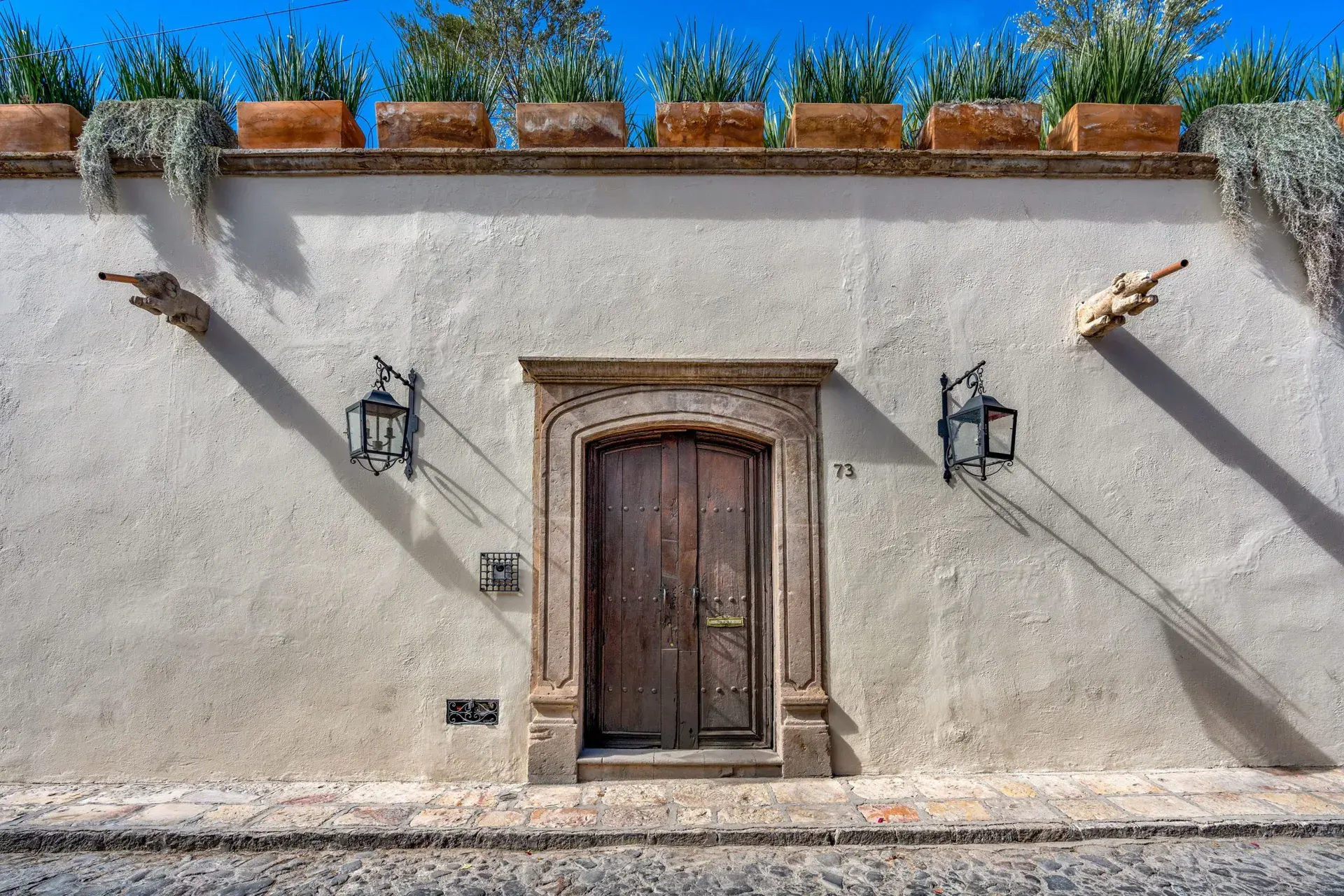 Casa Luz, white street facade with a carved stone doorframe and a wood door, San Miguel de Allende