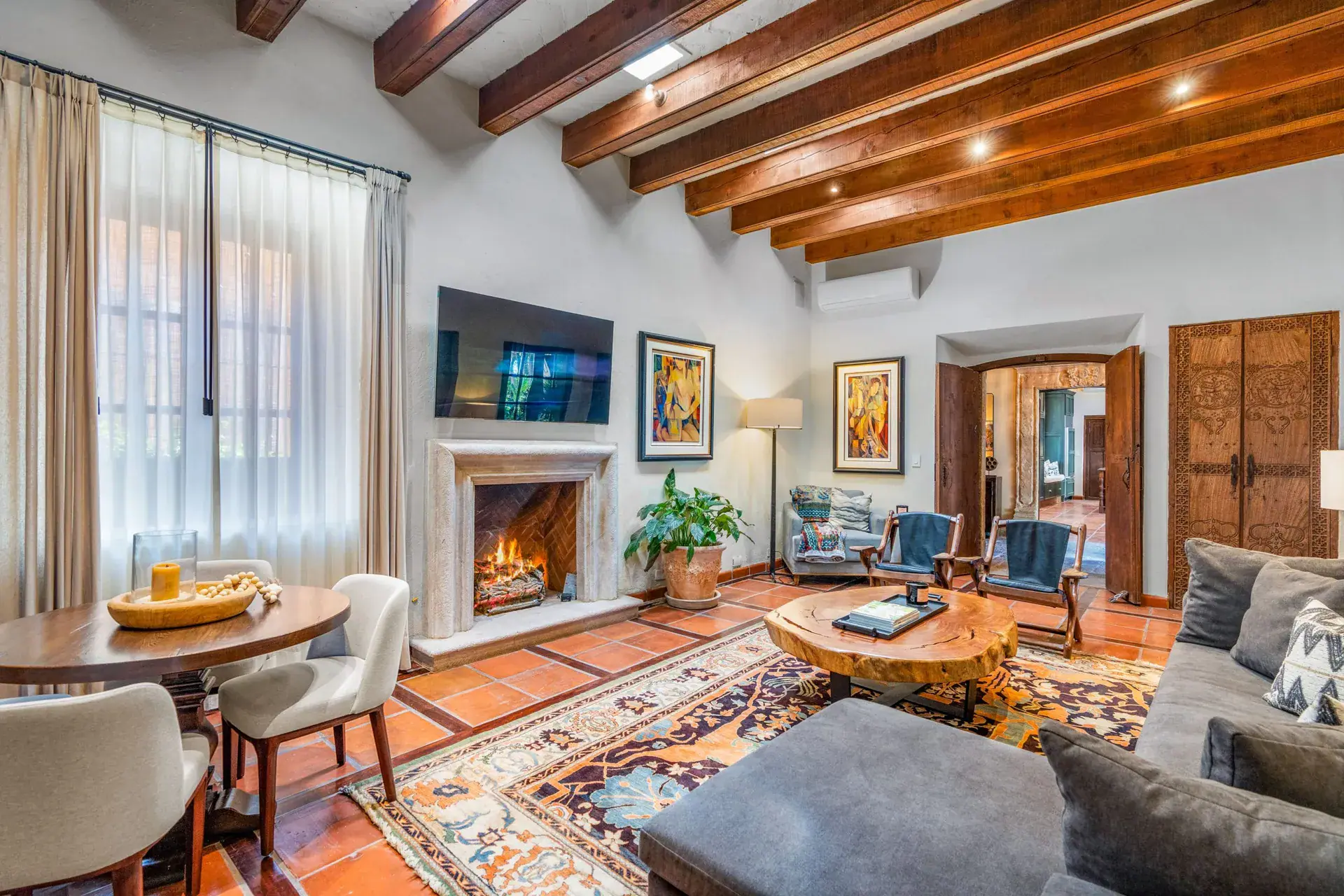 Casa Luz, living room with a fireplace, gray sectional and exposed wood beams, San Miguel de Allende