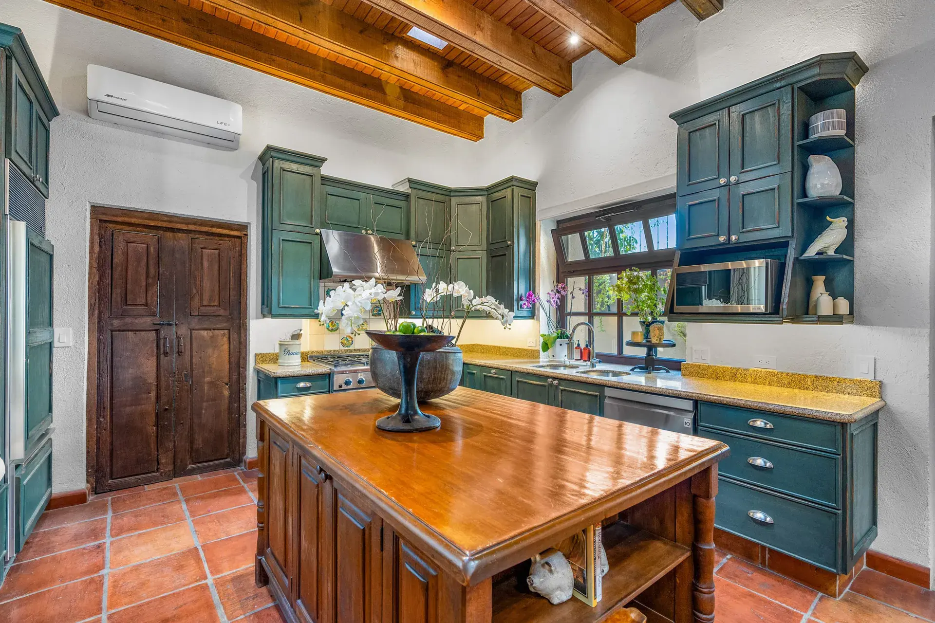 Casa Luz, kitchen with teal cabinets, a wood center island and terracotta floors, San Miguel de Allende