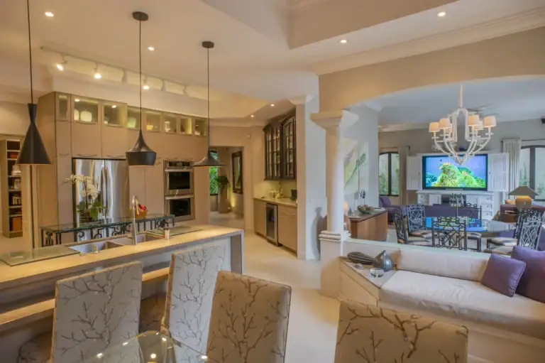 Casa Lyla, open kitchen with taupe cabinets, pendant lights, an island and a view to the family room, San Miguel de Allende