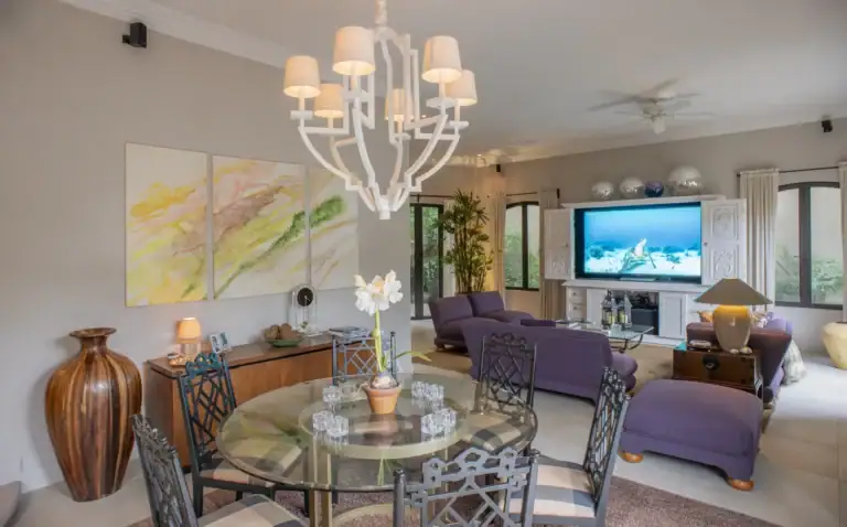 Casa Lyla, family room and dining area with a white chandelier, a glass dining table and purple seating, San Miguel de Allende