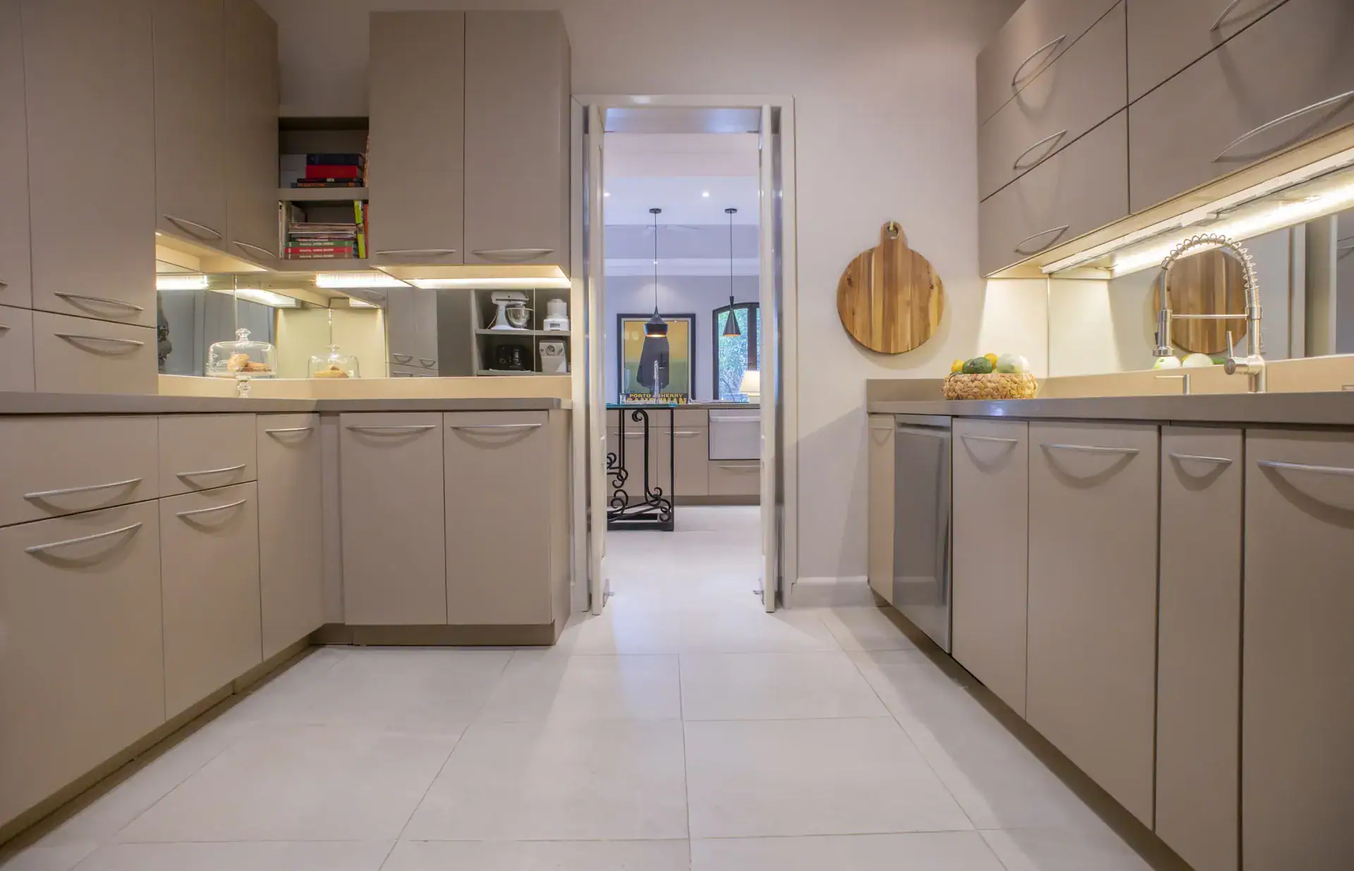 Casa Lyla, kitchen with taupe cabinets, mirrored backsplash and a view through to a hallway, San Miguel de Allende