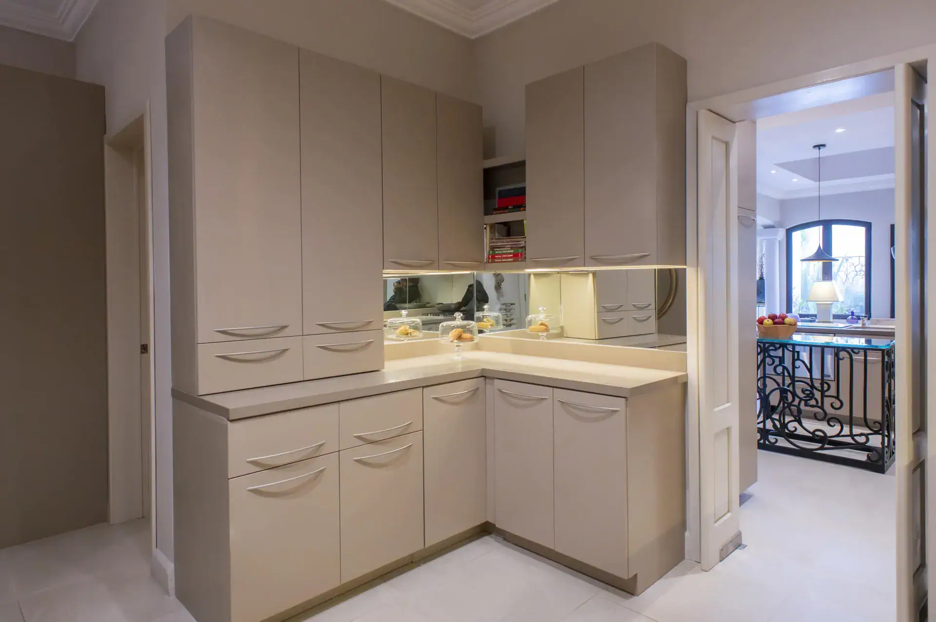 Casa Lyla, kitchen corner with taupe cabinets and a view to the hall through a double door, San Miguel de Allende