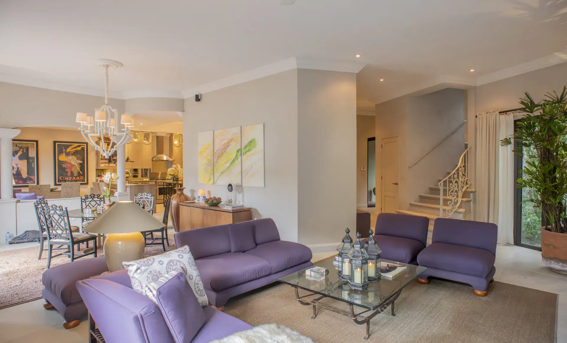 Casa Lyla, living room with purple sofas, a glass coffee table, a chandelier and a view to the kitchen, San Miguel de Allende