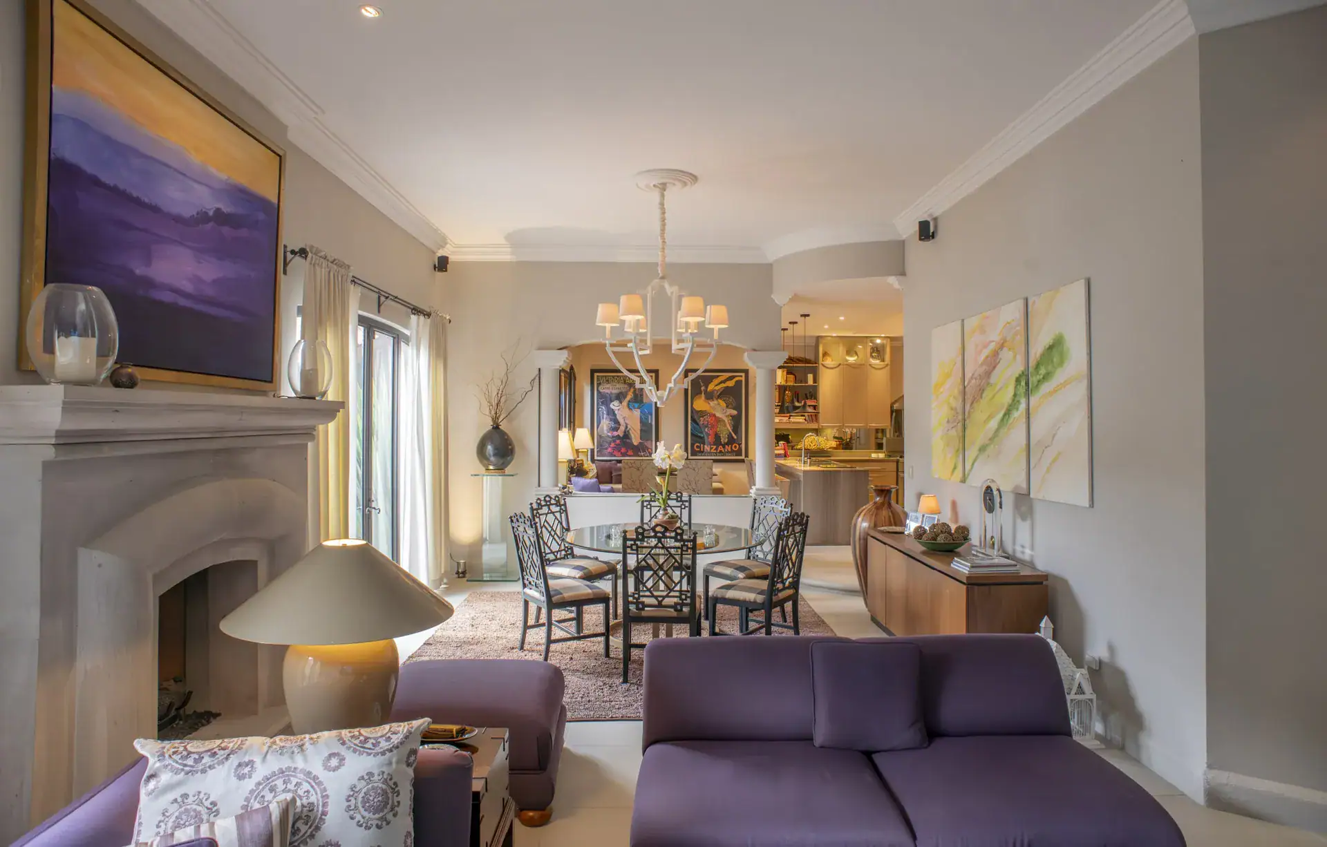 Casa Lyla, living room with a stone fireplace, purple sofas and an amber painting, San Miguel de Allende
