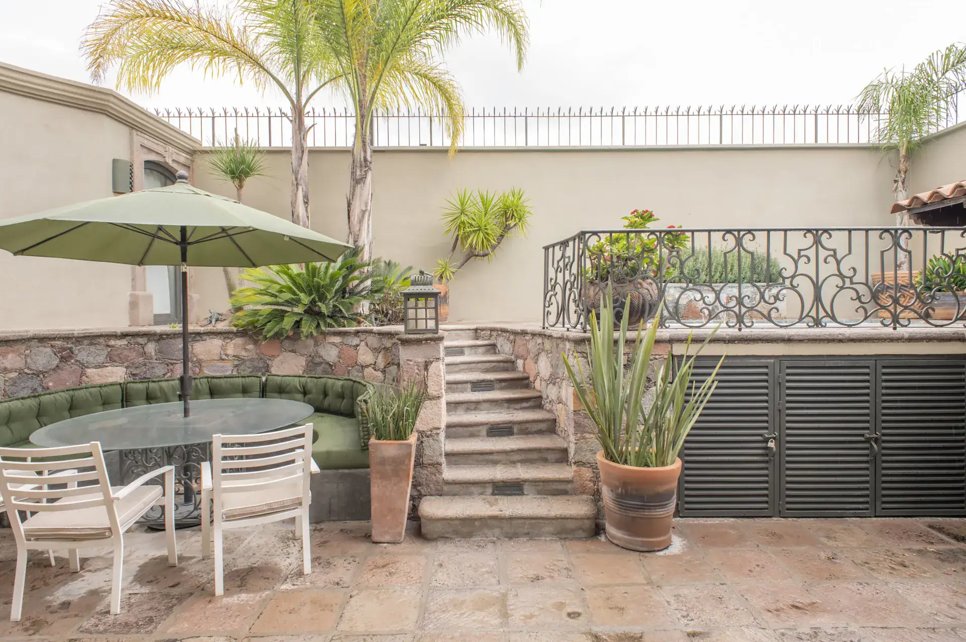 Casa Lyla, patio with an umbrella table, a stone staircase and a wrought-iron railing, San Miguel de Allende