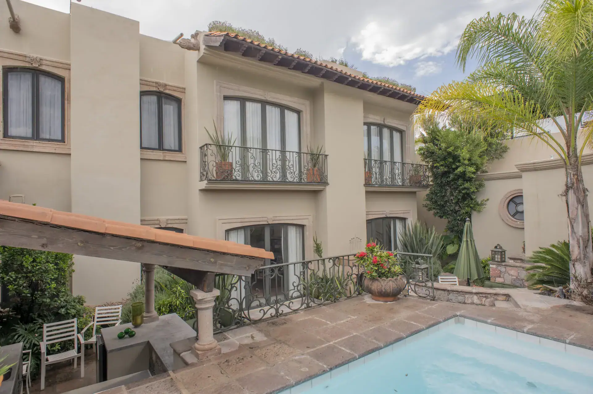 Casa Lyla, swimming pool, the two-story house and a covered pergola with palms, San Miguel de Allende