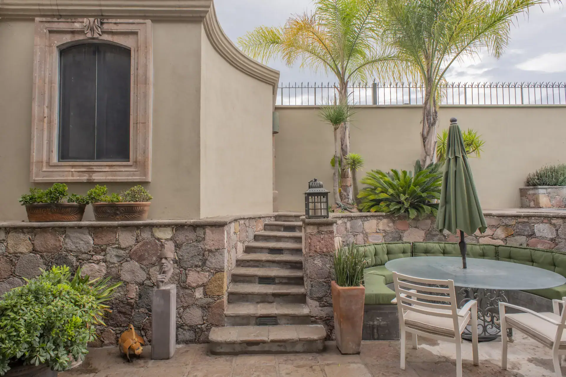 Casa Lyla, pool-side patio with a stone staircase, a round table and a window with wood shutters, San Miguel de Allende