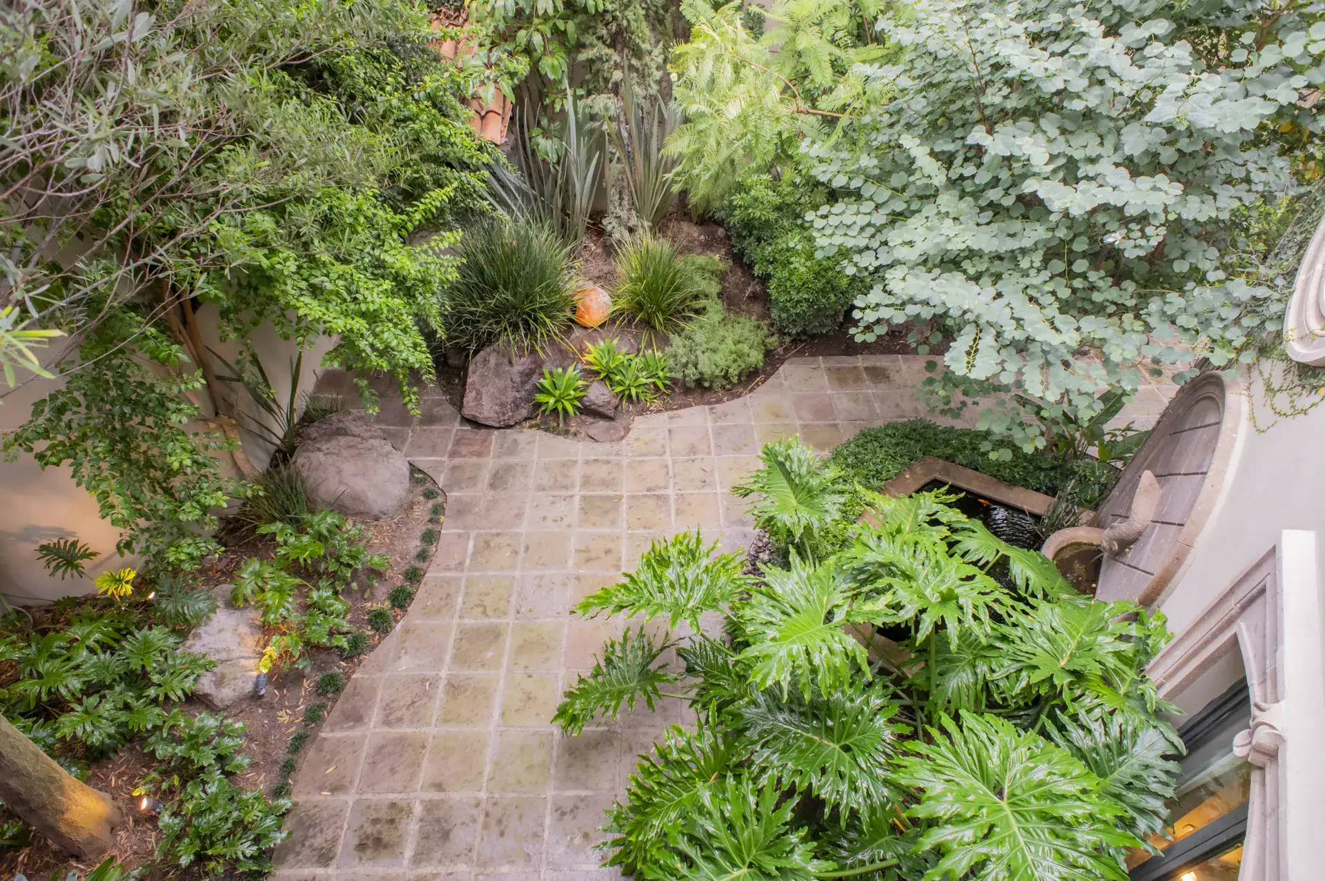 Casa Lyla, aerial view of the garden courtyard with a flagstone path and tropical plants, San Miguel de Allende