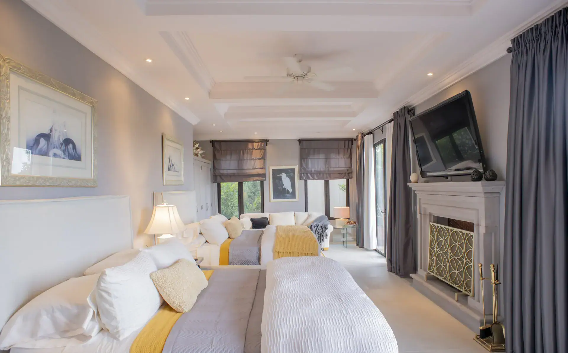 Casa Lyla, large bedroom with two beds, a wall-mounted television, a fireplace and a ceiling fan, San Miguel de Allende