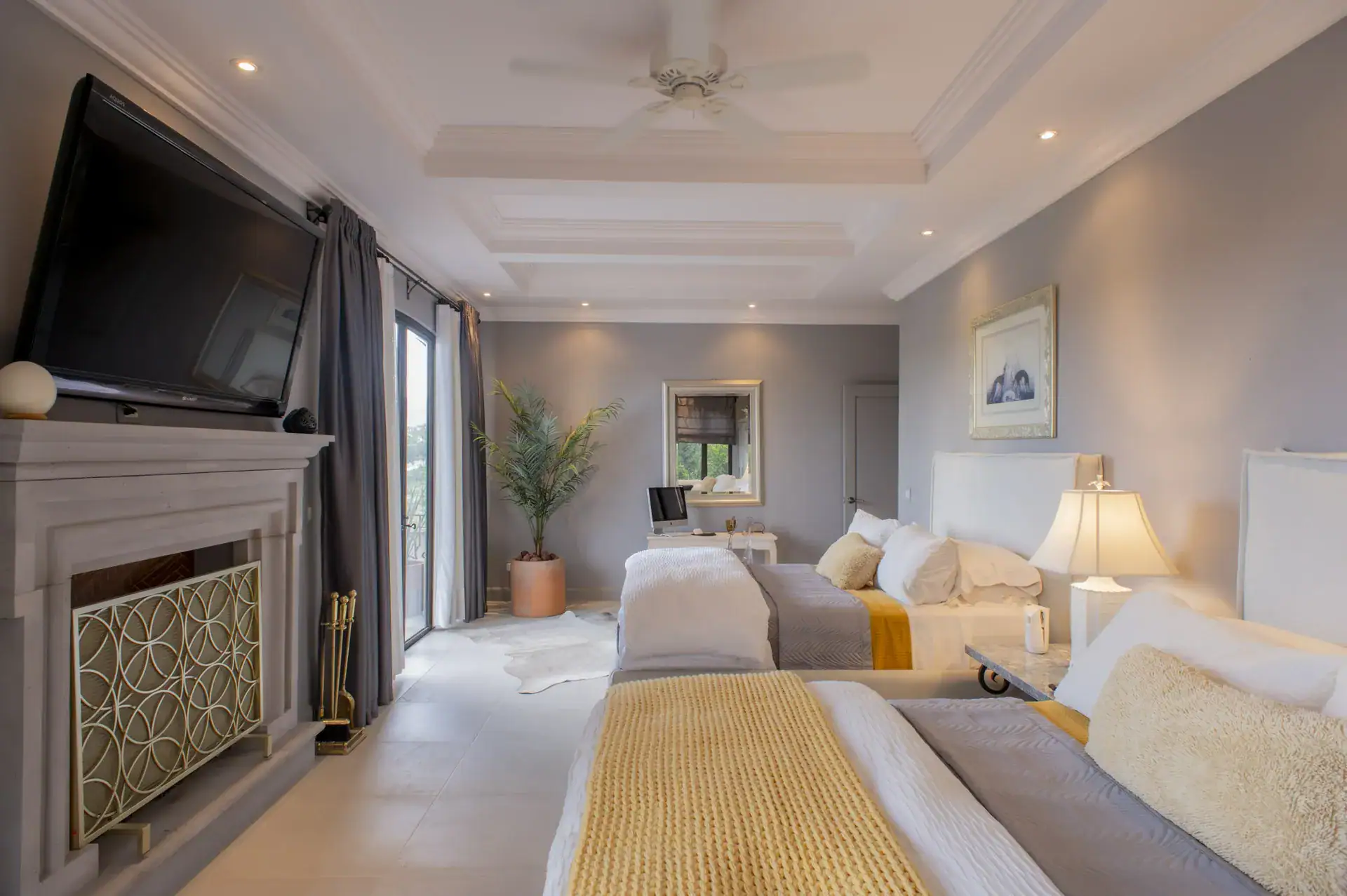 Casa Lyla, suite with twin beds with gray and yellow bedding, a fireplace and a television, San Miguel de Allende