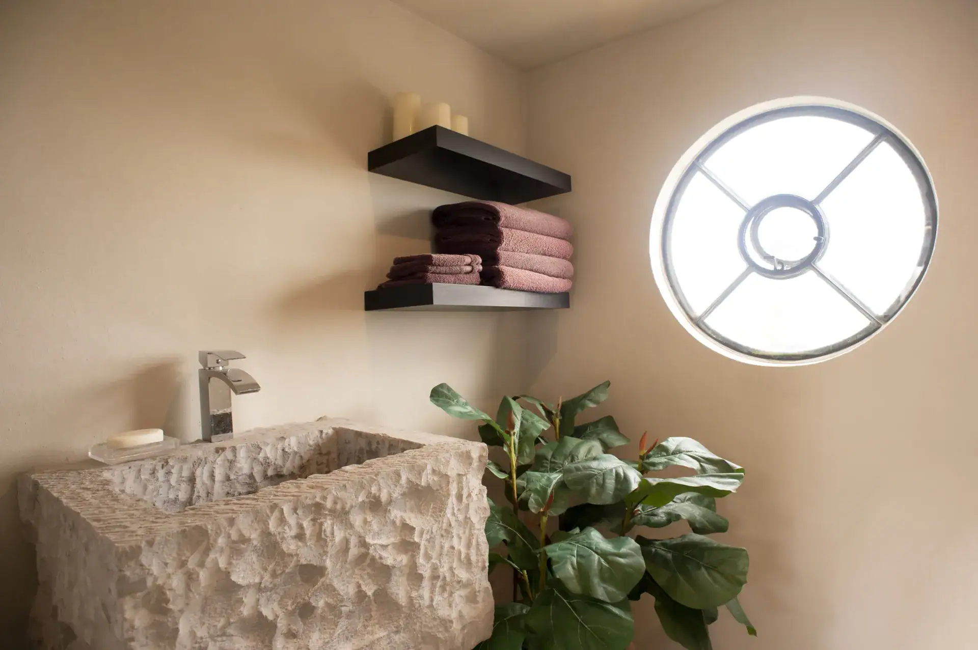 Casa Lyla, bathroom with a rough carved stone sink and a round window, San Miguel de Allende