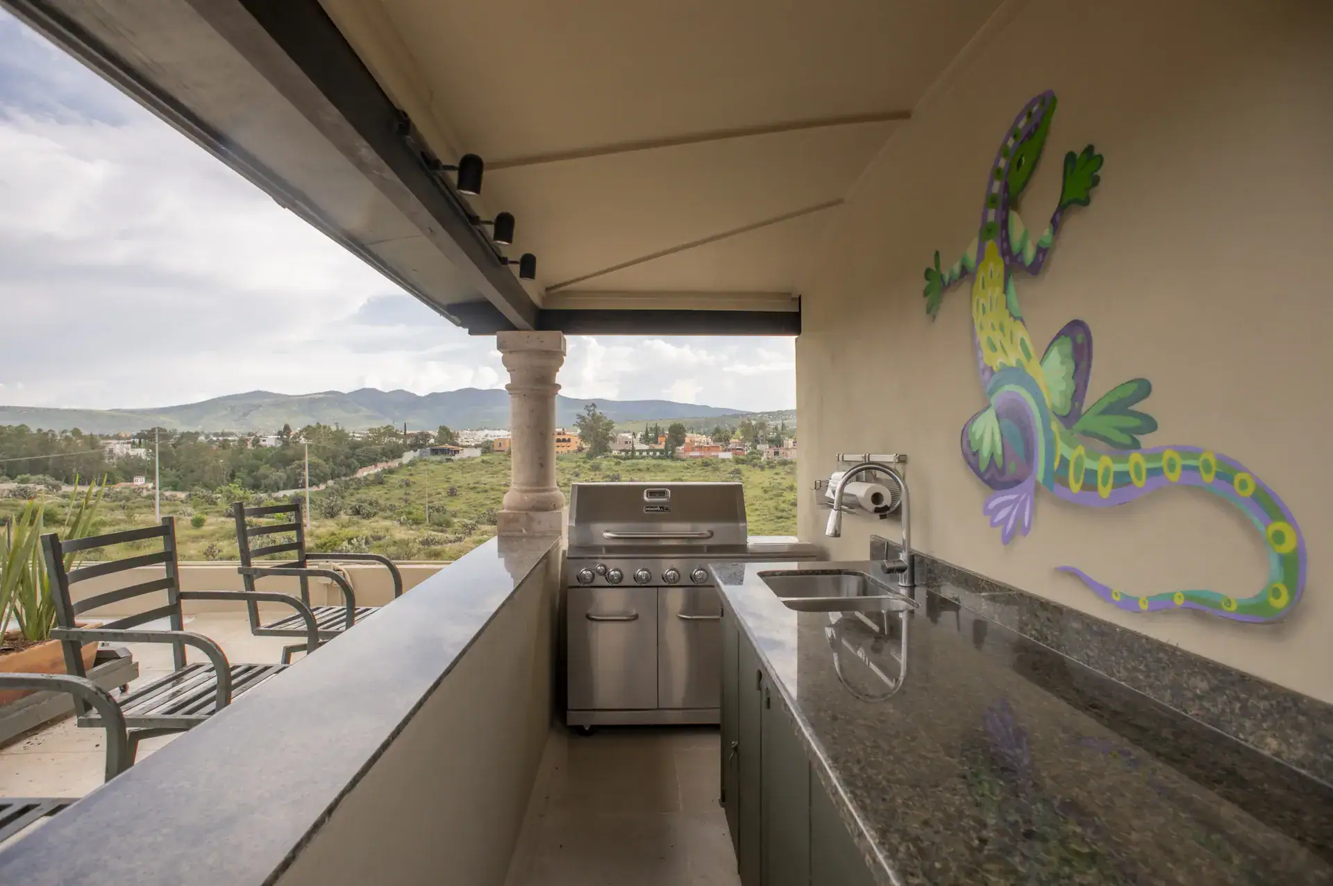 Casa Lyla, rooftop outdoor kitchen counter with a stainless grill and a painted gecko on the wall, San Miguel de Allende