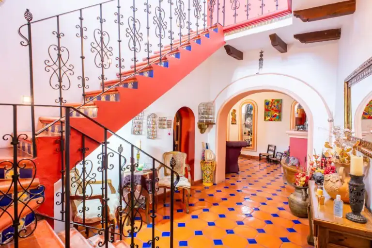Casa Mexicana, entry hall with a red staircase with a wrought-iron railing and a blue and orange tile floor, San Miguel de Allende