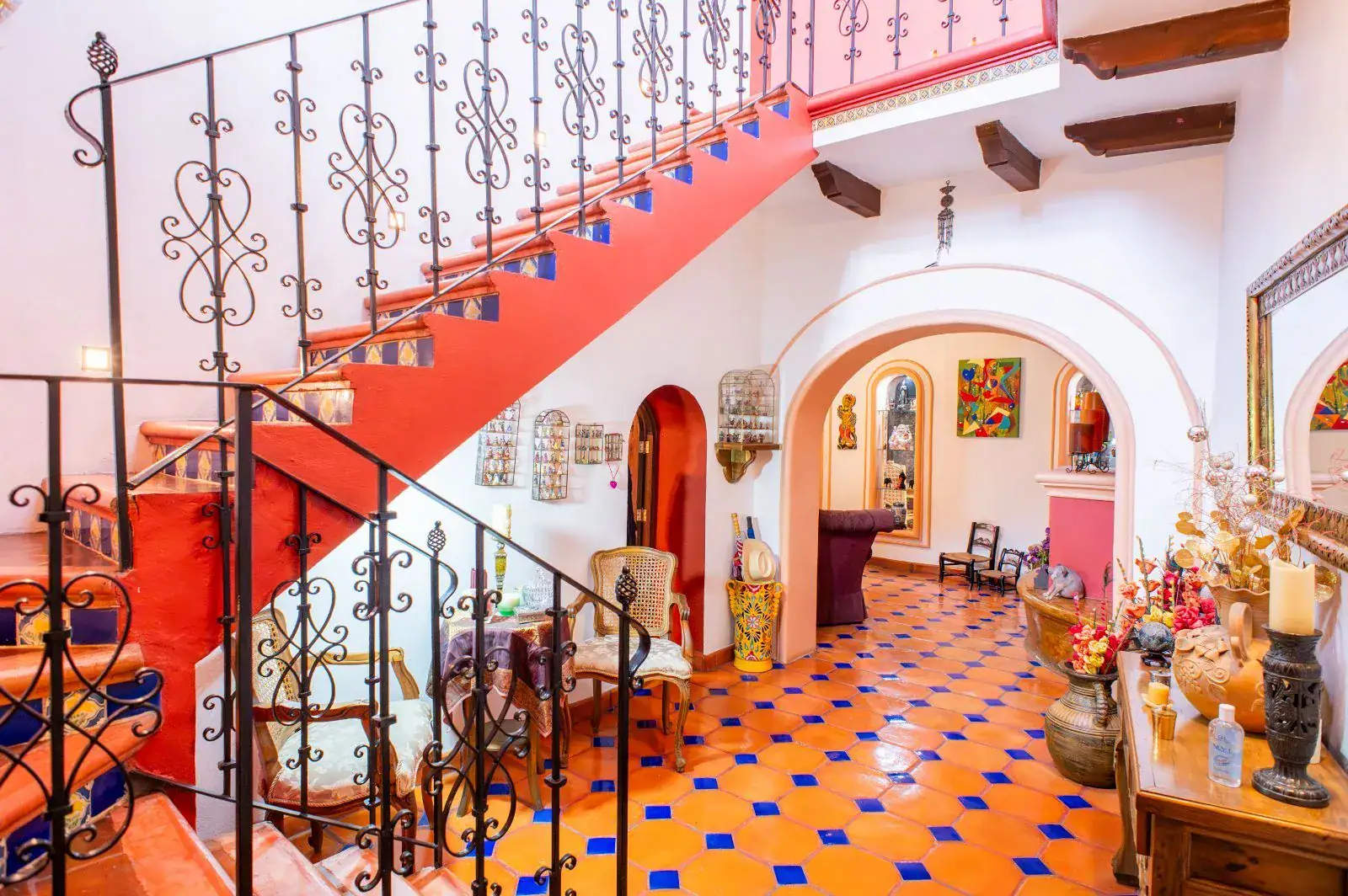 Casa Mexicana, entry hall with a red staircase with a wrought-iron railing and a blue and orange tile floor, San Miguel de Allende