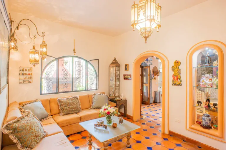 Casa Mexicana, living room with an orange sectional, an arched window, hanging lanterns and arched glass display niches, San Miguel de Allende