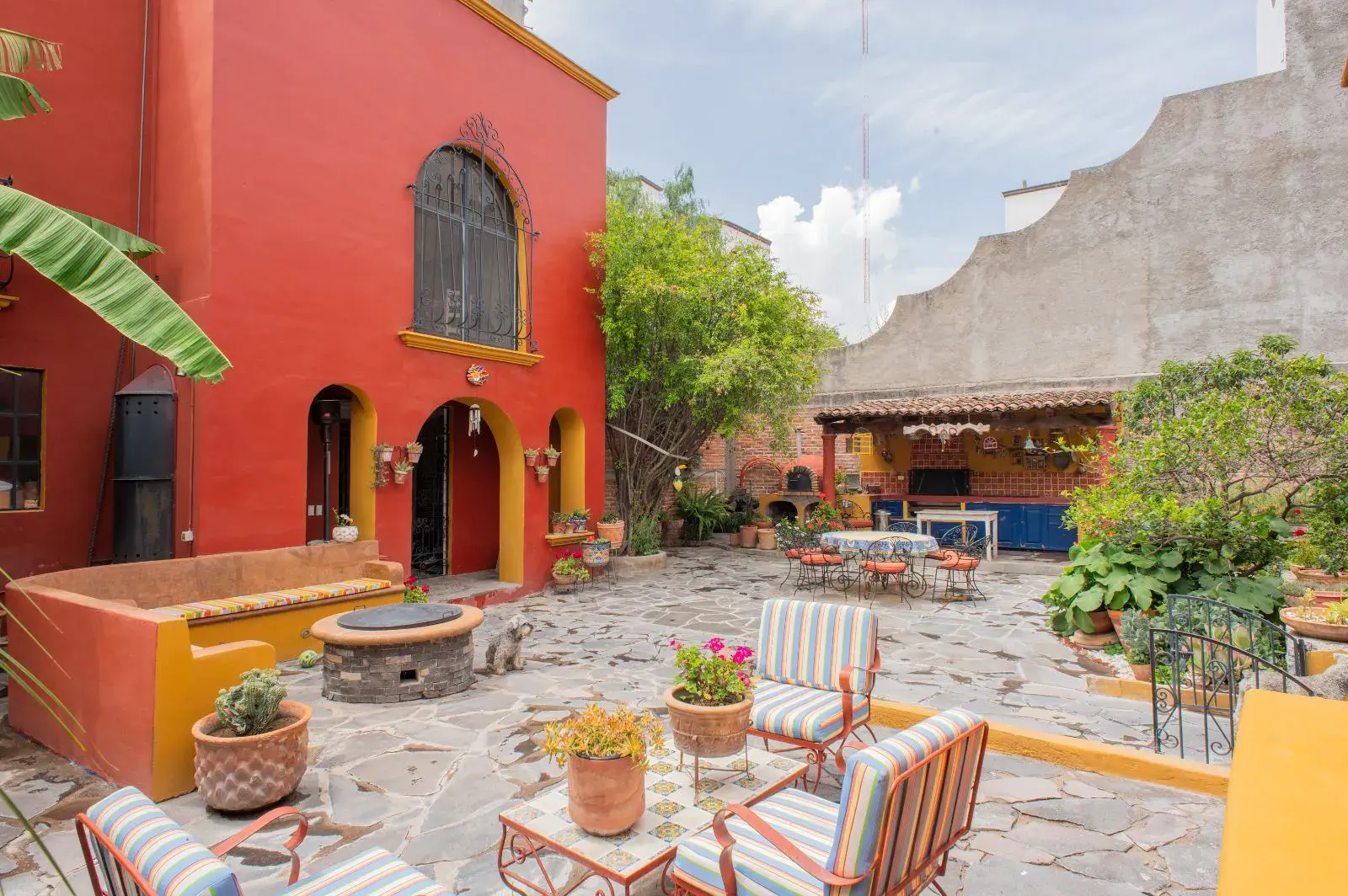 Casa Mexicana, courtyard with a flagstone floor, a stone fire pit, striped chairs and a covered outdoor kitchen, San Miguel de Allende