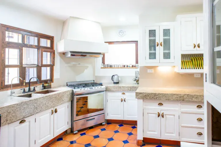 Casa Mexicana, kitchen with white cabinets, a stone sink counter, a stainless range and a blue and orange tile floor, San Miguel de Allende
