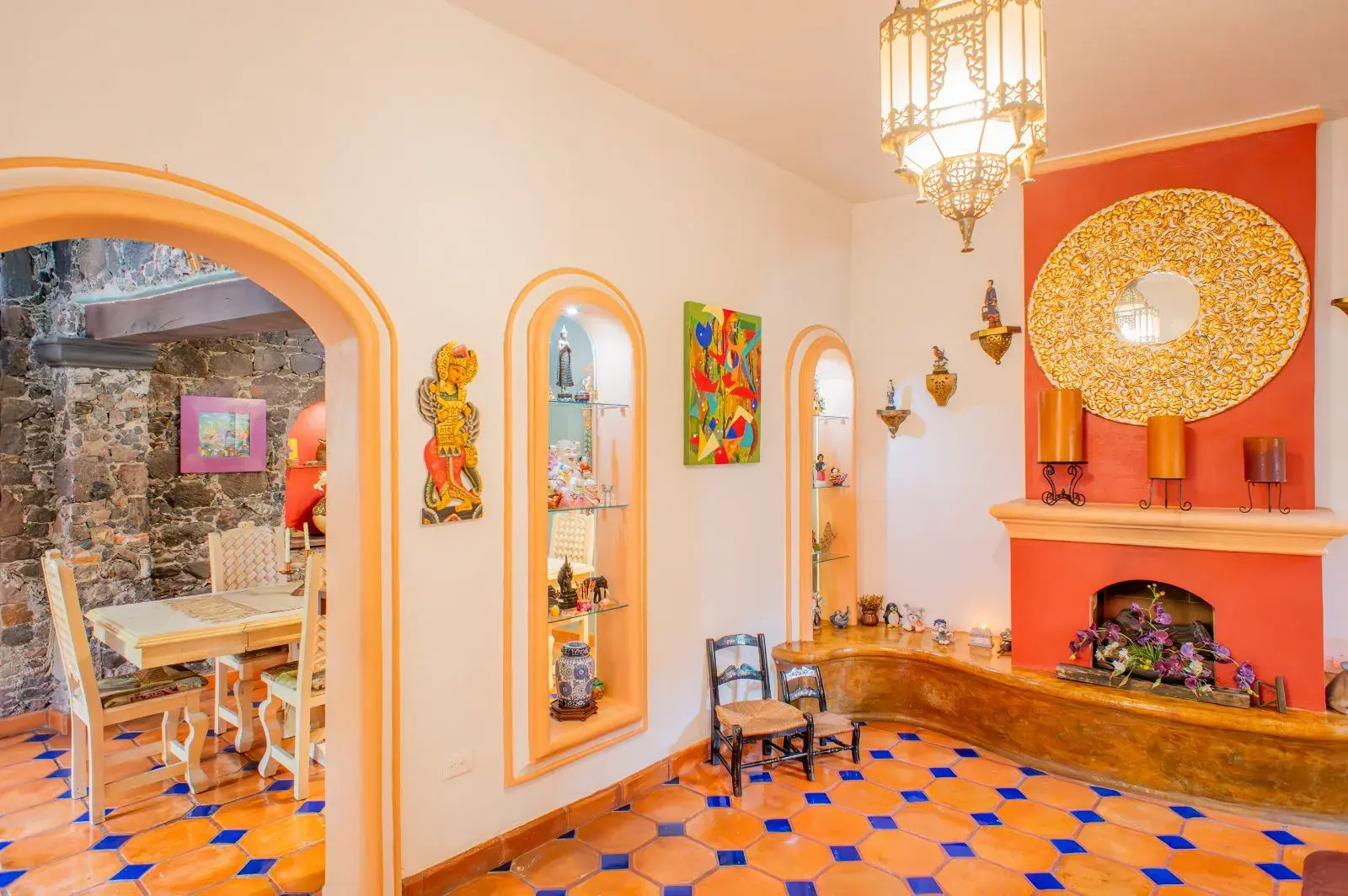Casa Mexicana, living room with arched niches, a red fireplace, a gold mirror and a view to a dining table, San Miguel de Allende
