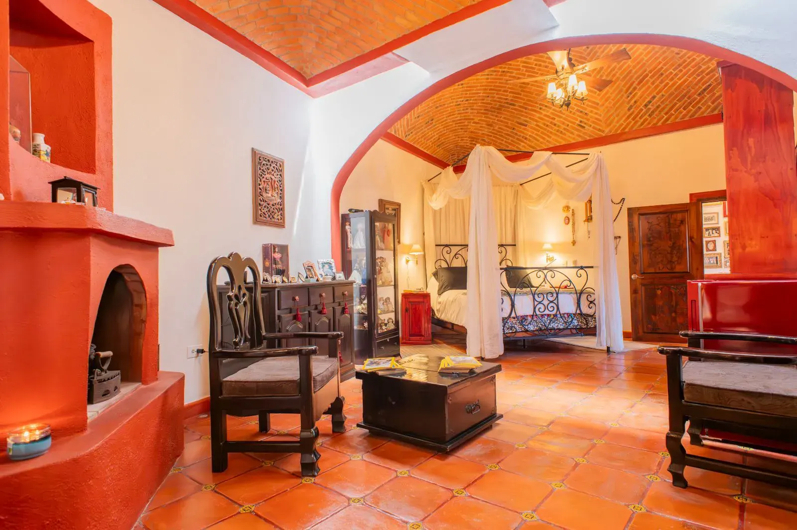 Casa Mexicana, bedroom suite with a red fireplace, a canopy bed, carved wood chairs and a brick vaulted ceiling, San Miguel de Allende