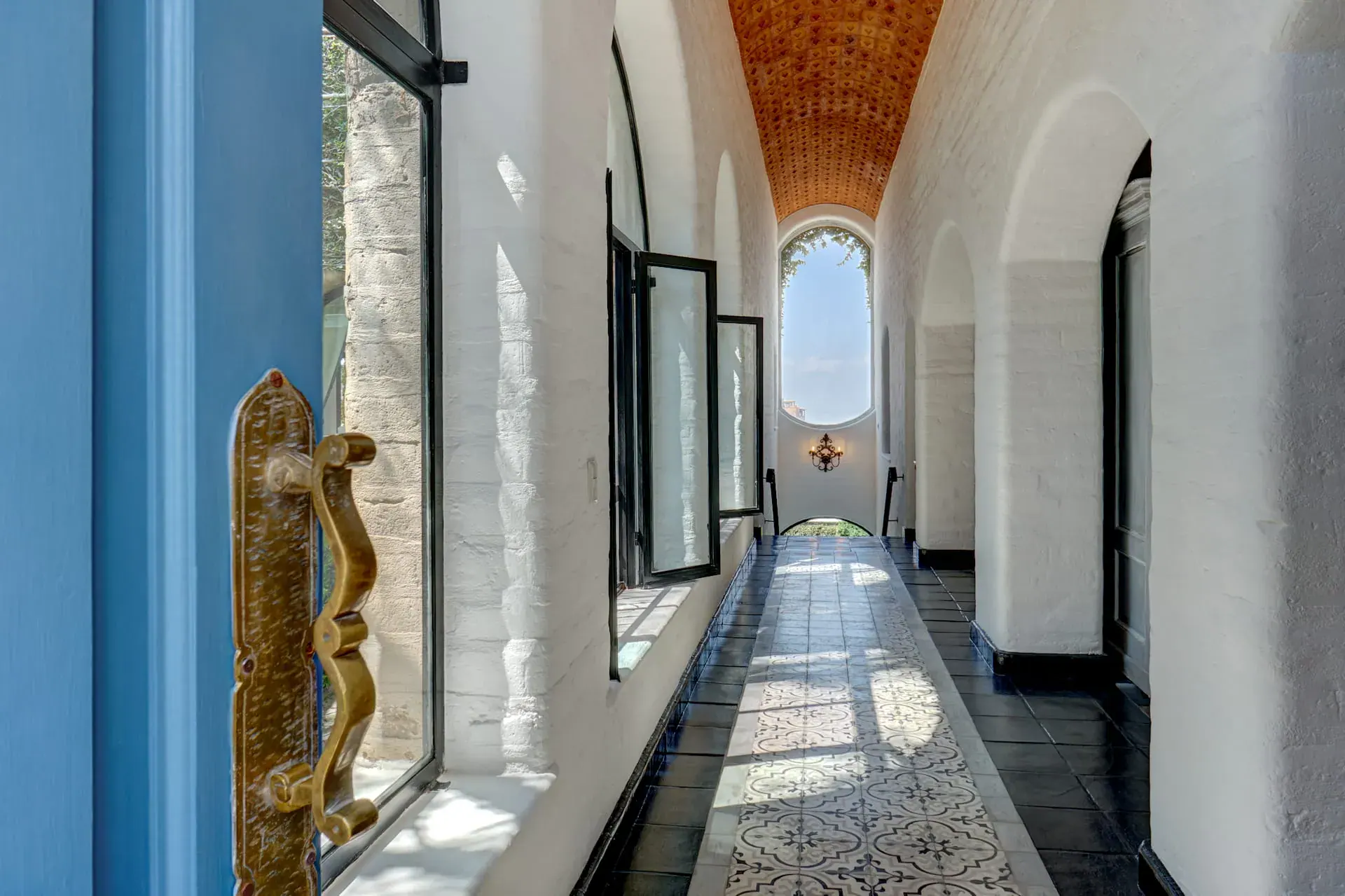Casa Mi Besito, long arched corridor with a brick vaulted ceiling, black tile floor and a window at the end, San Miguel de Allende