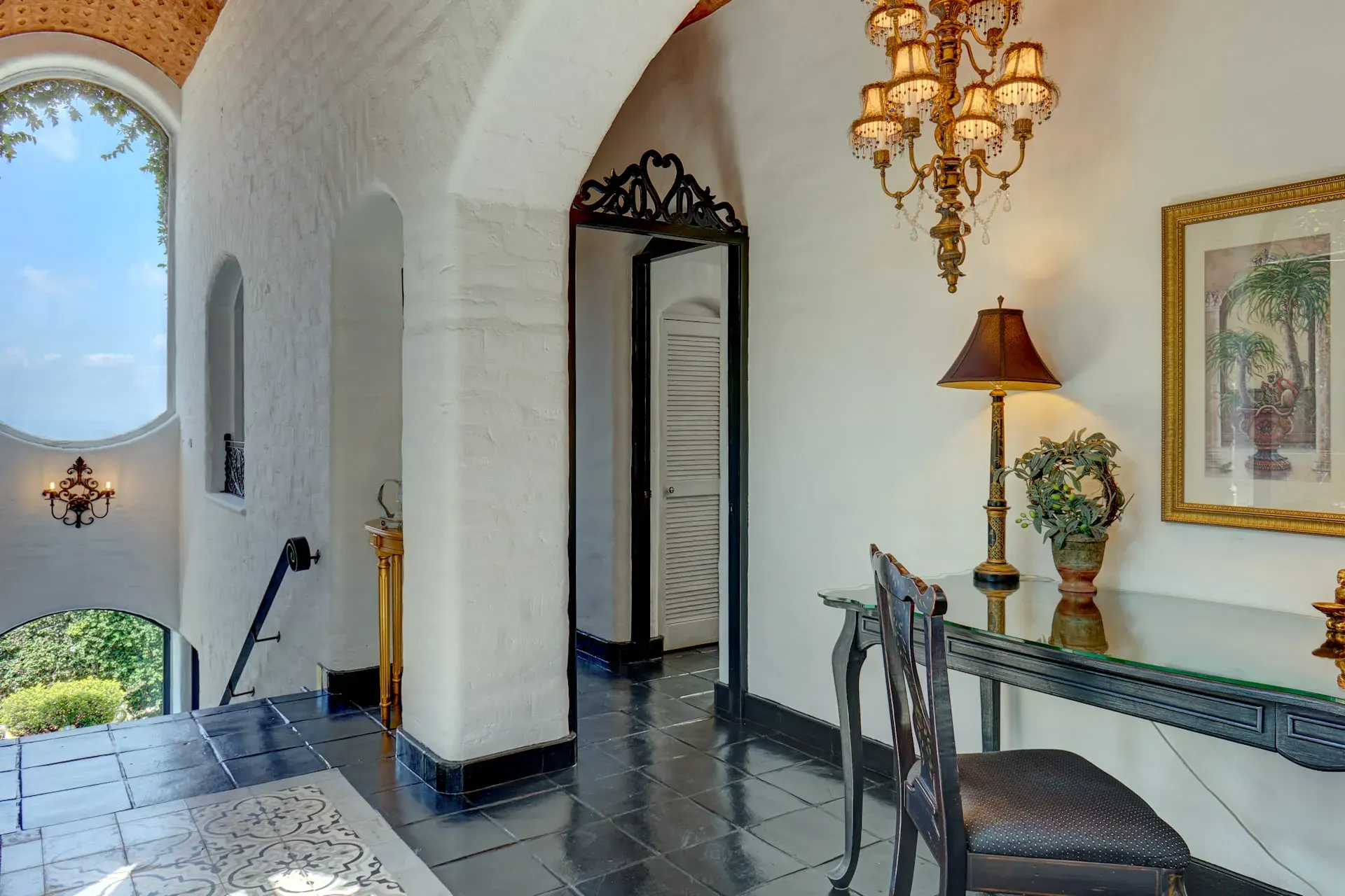 Casa Mi Besito, arched landing with a writing desk, a gold chandelier, black tile floor and a glimpse of the valley, San Miguel de Allende