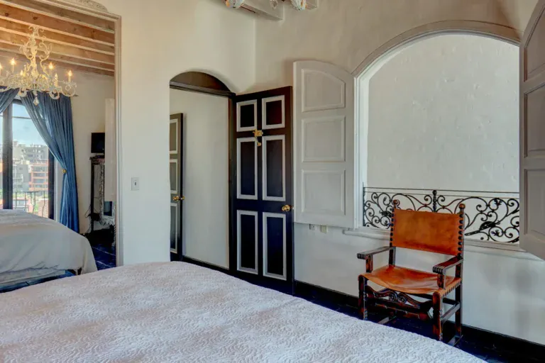 Casa Mi Besito, bedroom with a black and white door, an arched niche with a carved iron rail and a leather chair, San Miguel de Allende
